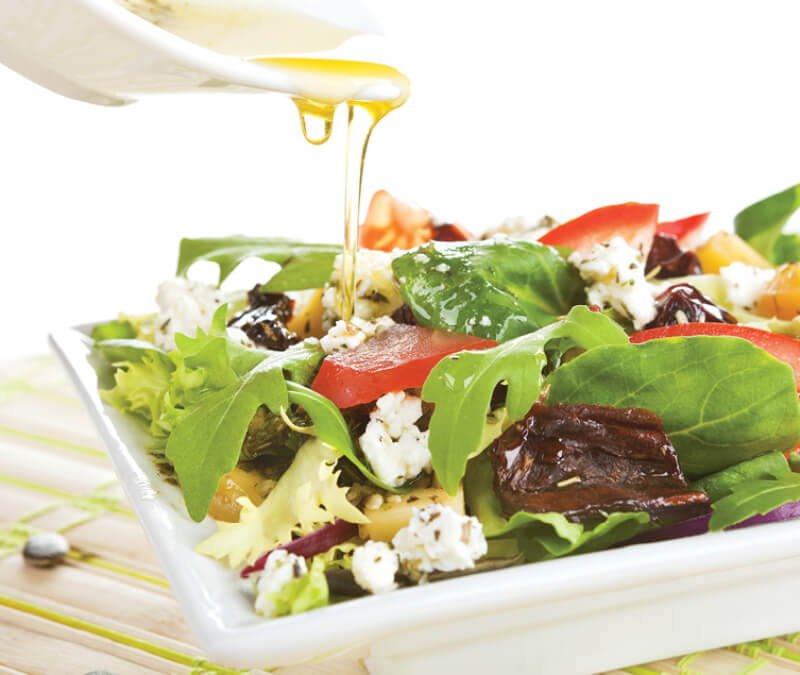 a salad getting drizzled with oil