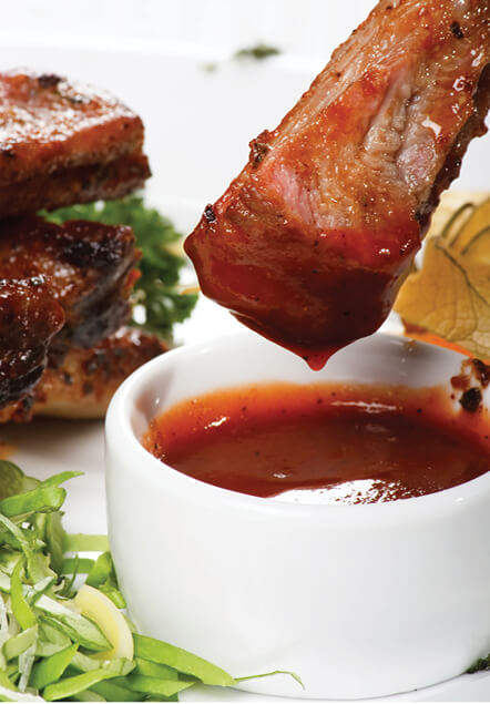 pork rib being dipped into barbeque suace