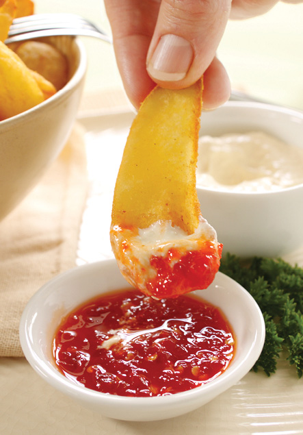 a potato wedge getting dipped into sweet chilli sauce